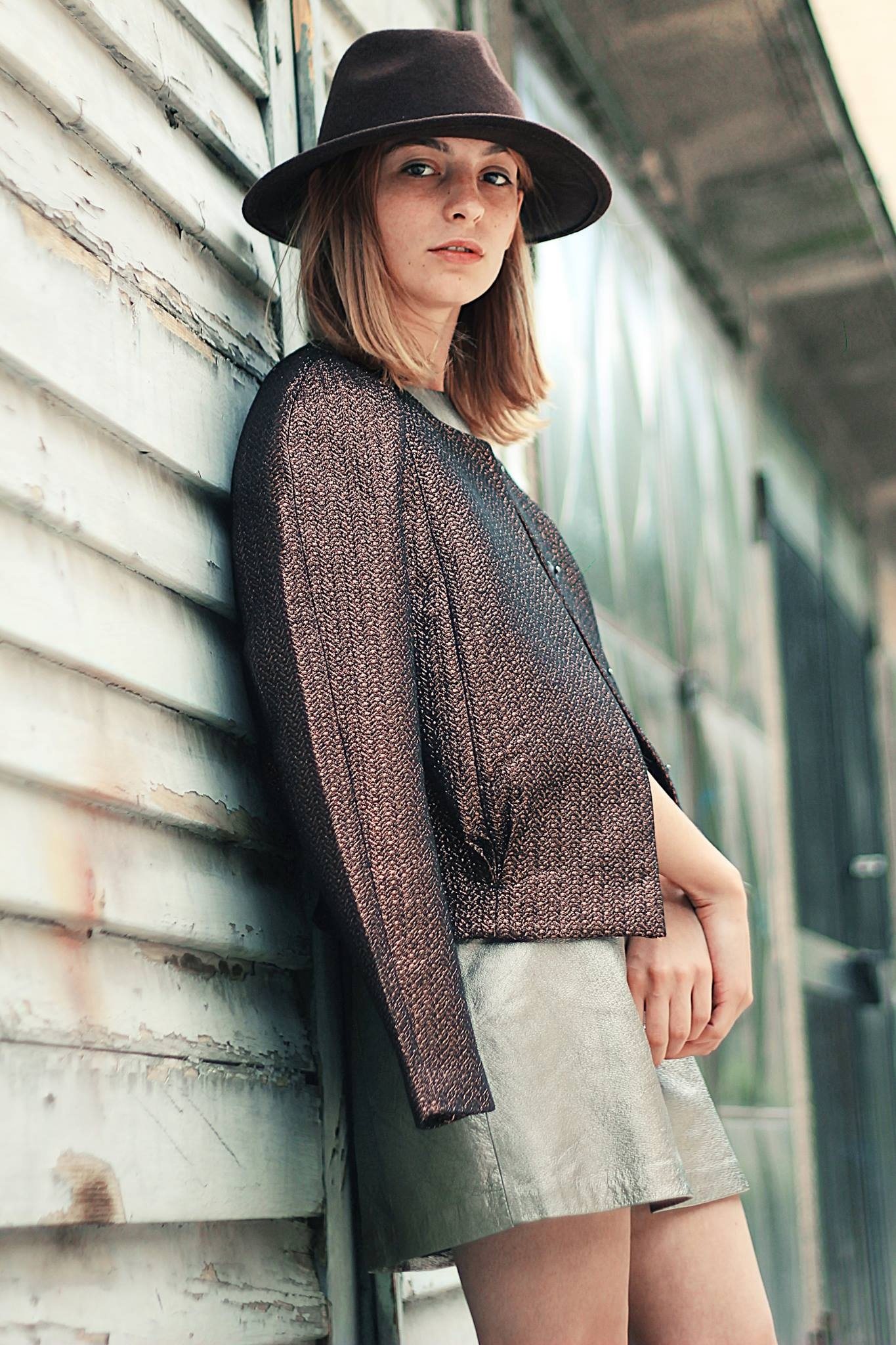Woman in a hat leaning on a wooden wall