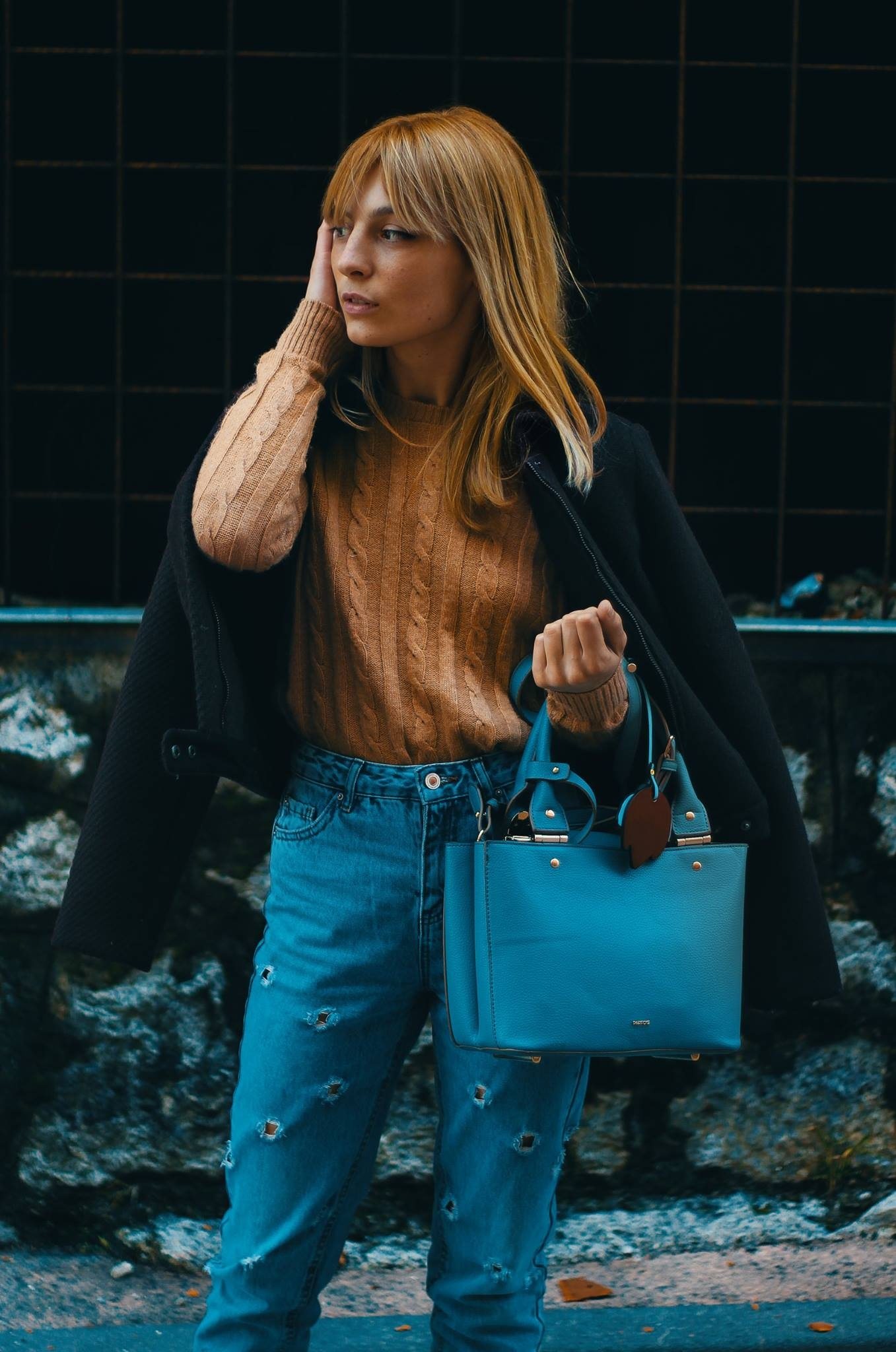 Woman with a blue bag against green tiles