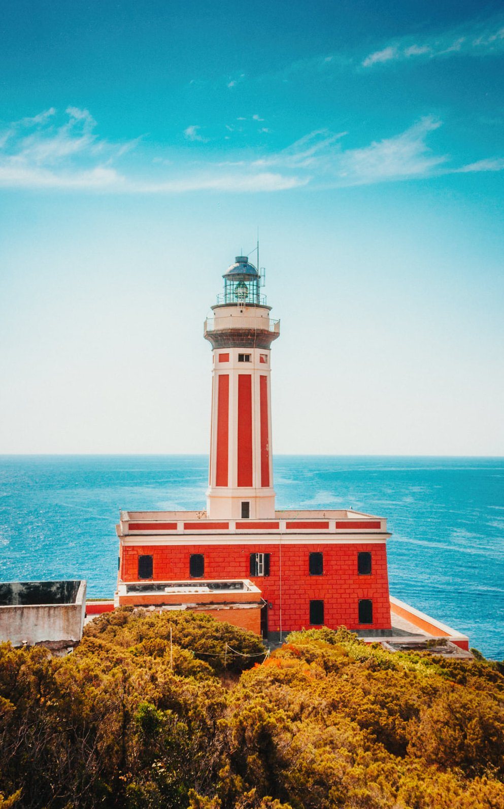 Red and white lighthouse against a turquoise sky