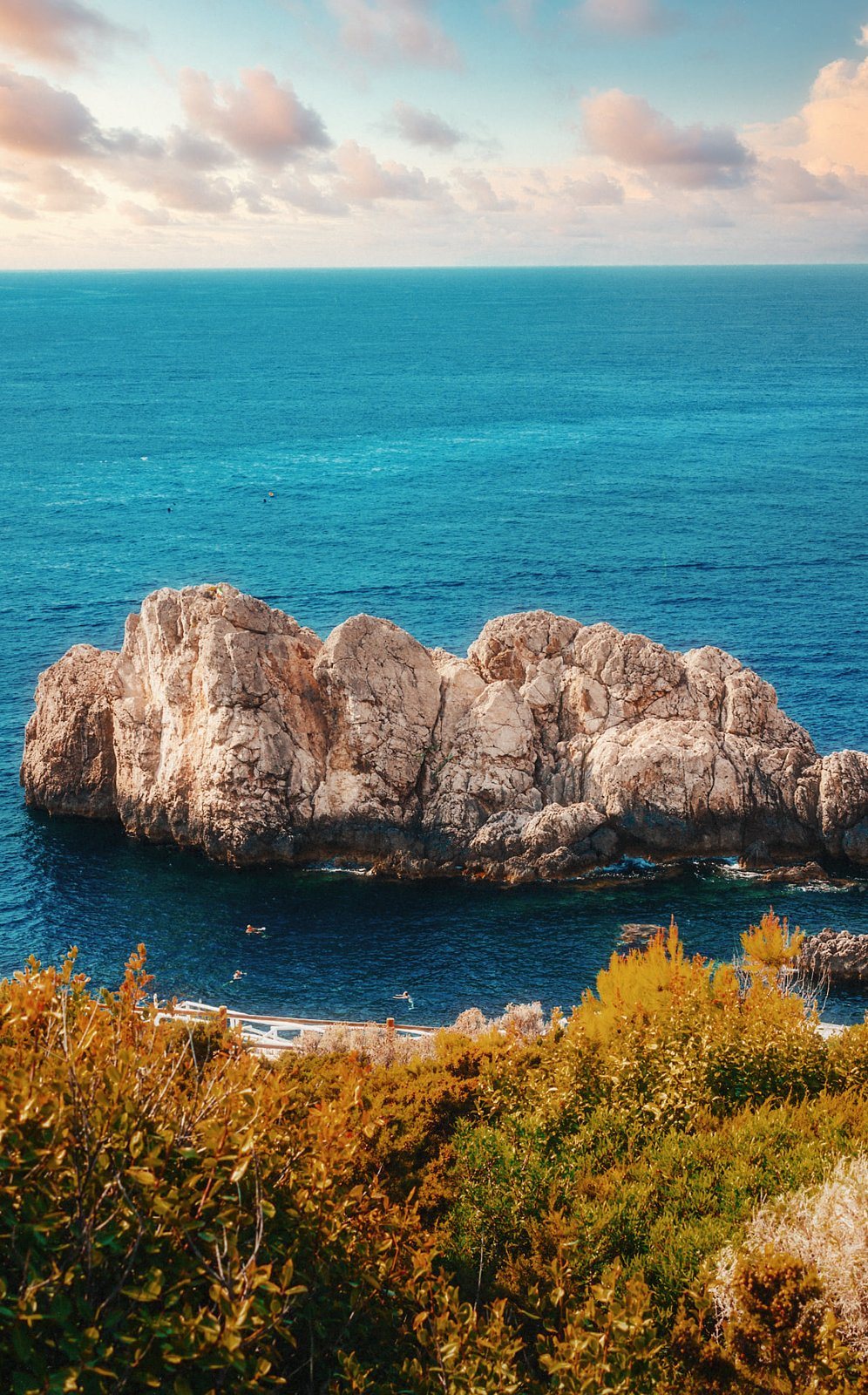 Rock in a turquoise sea at sunset