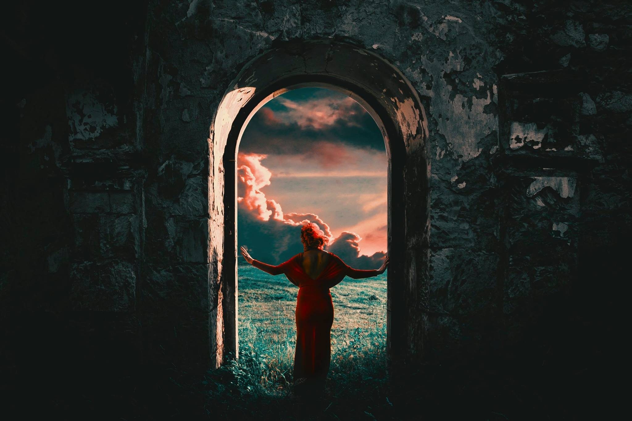 Woman in an archway under a pink sky