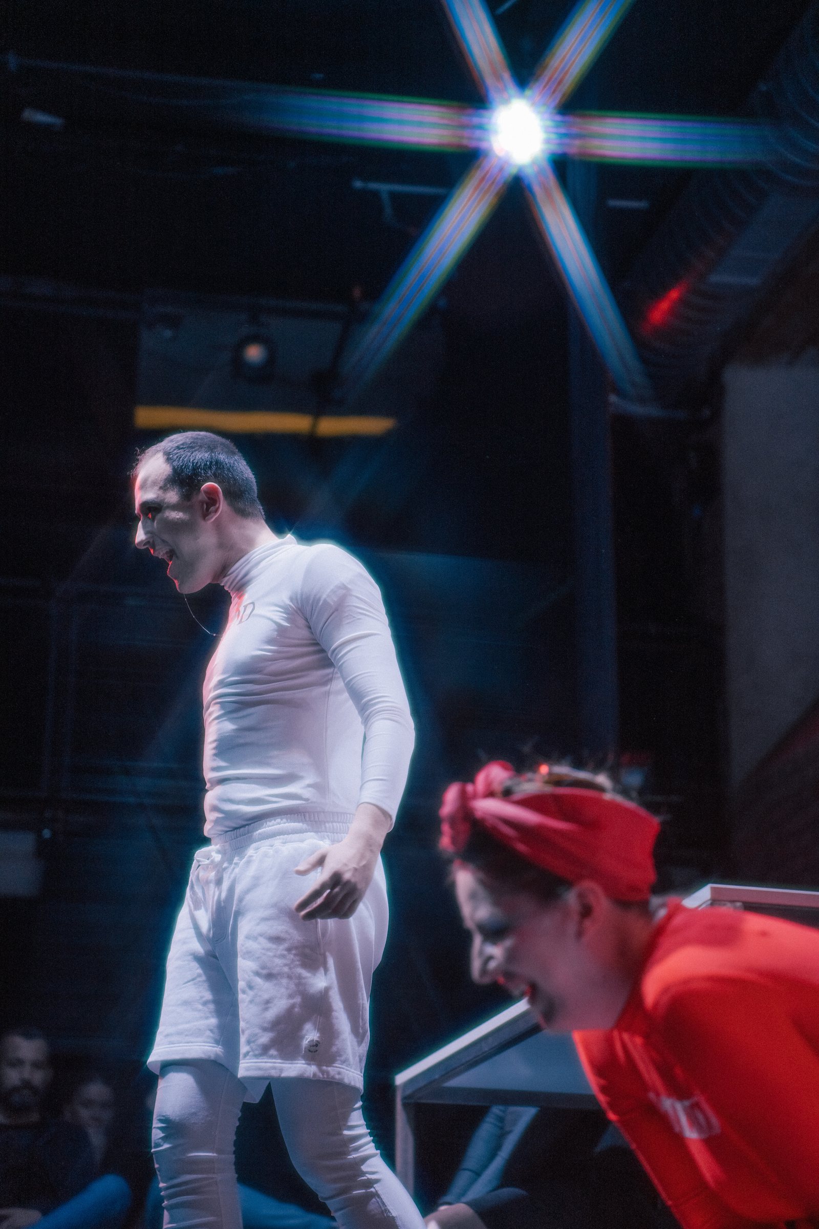 Two performers on stage under a burst of light