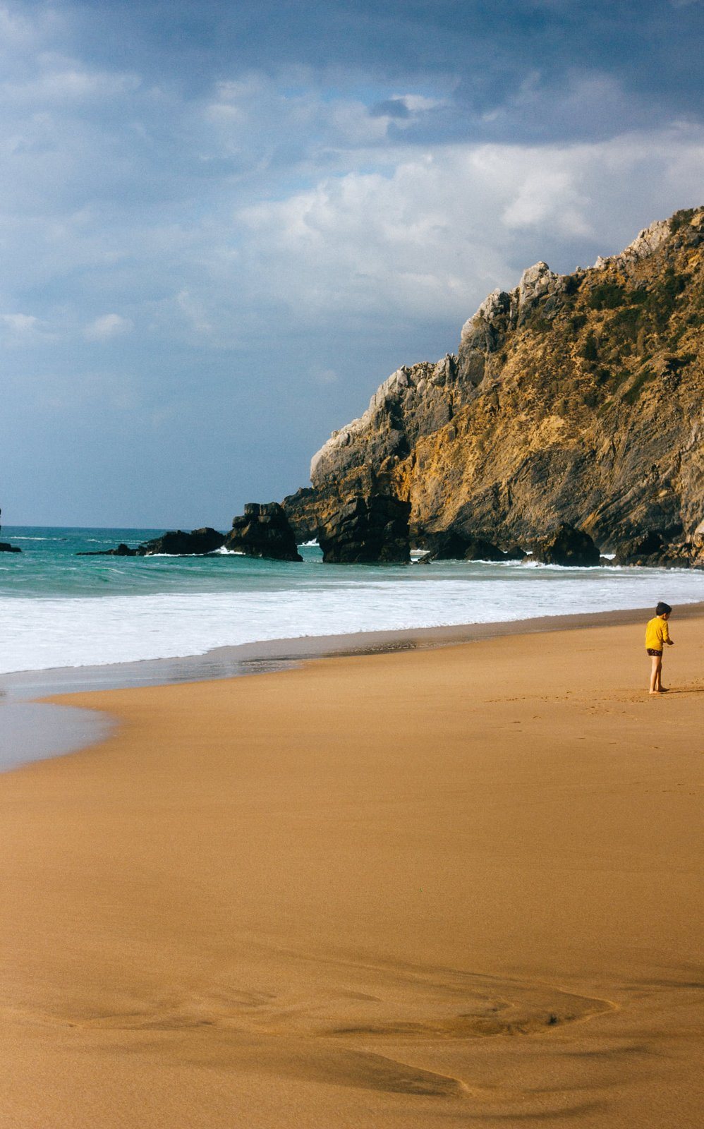Boy in a yellow shirt on an empty beach