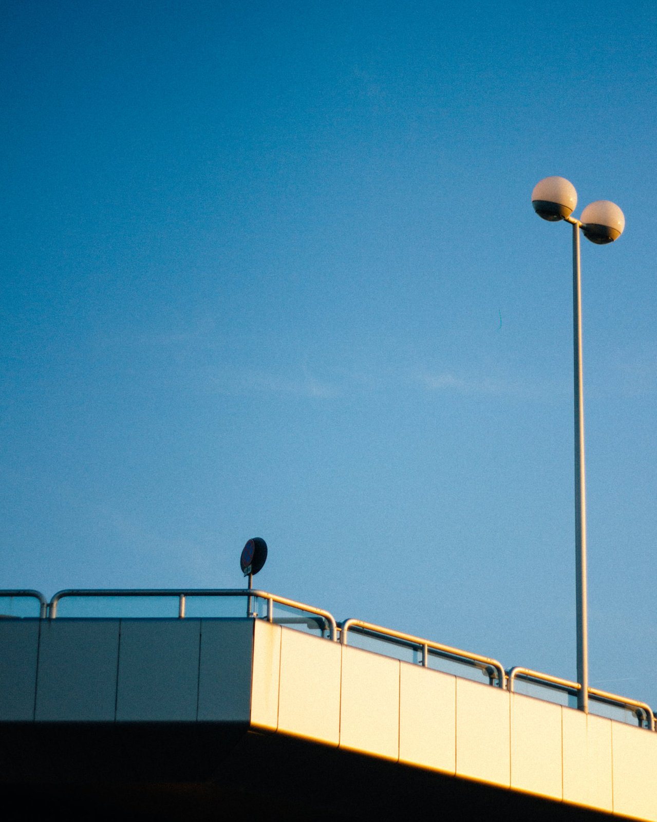 Overpass and two street lamps against a deep blue sky
