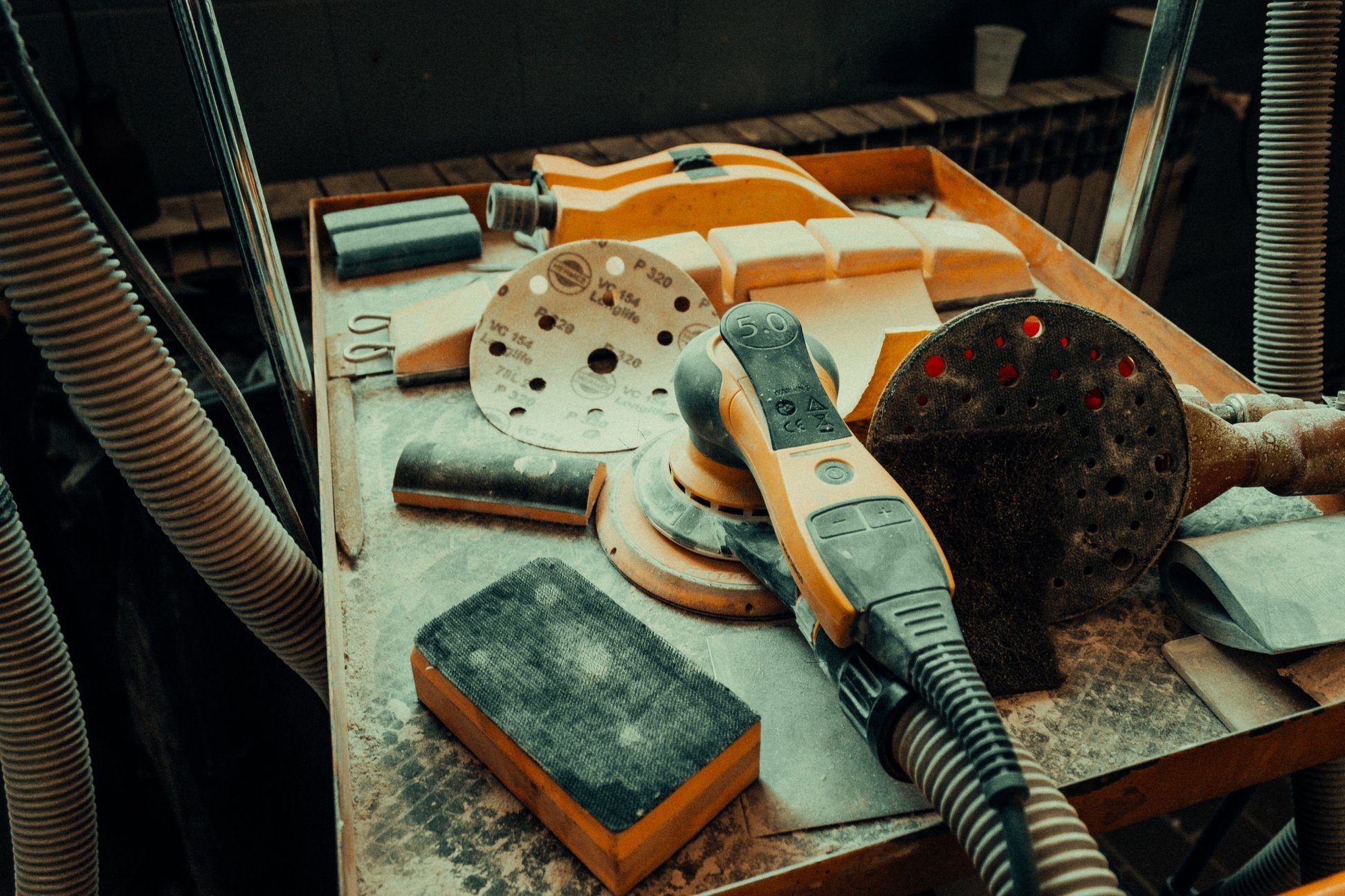 Orbital sander and discs on a dusty bench